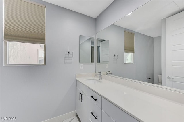 bathroom with toilet, baseboards, and vanity