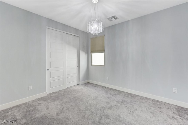 unfurnished bedroom with a closet, a chandelier, and carpet flooring