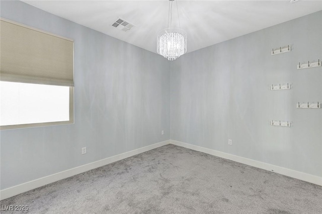 carpeted empty room with a chandelier, visible vents, and baseboards