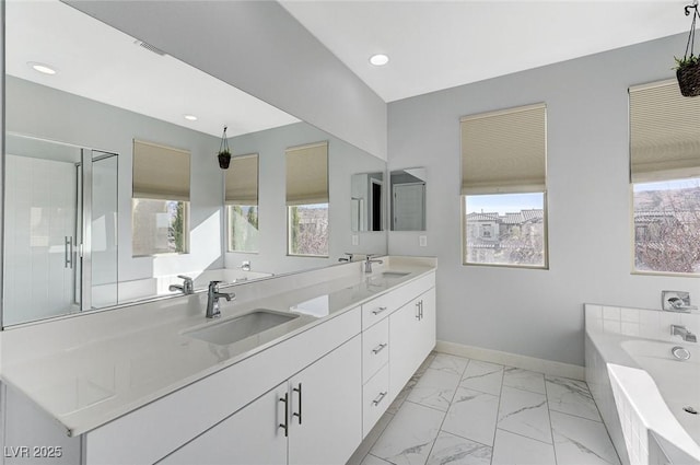 full bathroom featuring a garden tub, marble finish floor, a sink, and baseboards