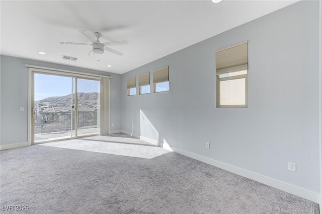 carpeted empty room with ceiling fan and a mountain view