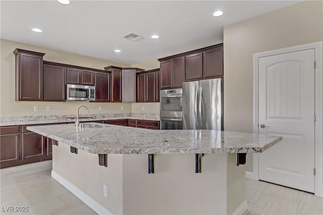 kitchen featuring a breakfast bar area, appliances with stainless steel finishes, a kitchen island with sink, and sink