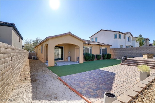 rear view of property featuring cooling unit, a lawn, and a patio