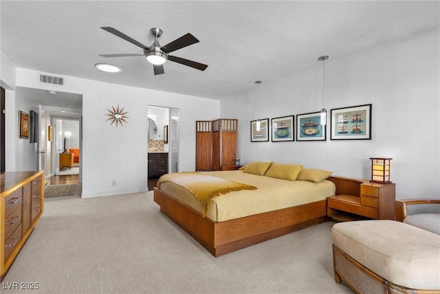 bedroom featuring ensuite bath, light colored carpet, and ceiling fan