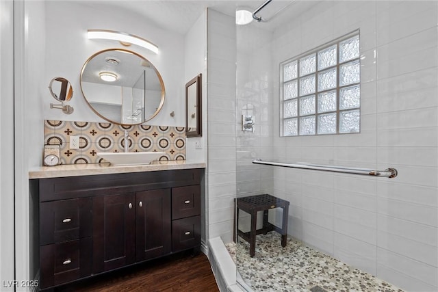 bathroom with wood-type flooring, vanity, and a tile shower