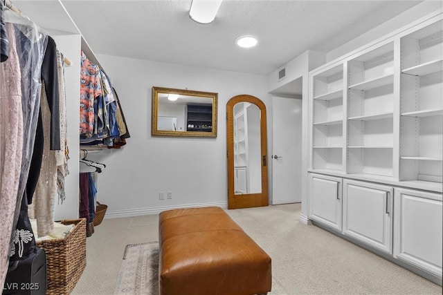 walk in closet with light colored carpet and french doors