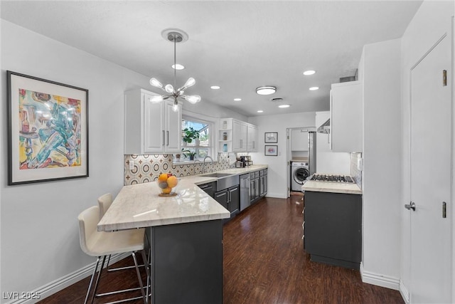 kitchen featuring washer / dryer, white cabinetry, hanging light fixtures, backsplash, and a breakfast bar