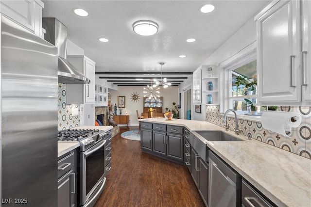 kitchen featuring white cabinetry, appliances with stainless steel finishes, backsplash, decorative light fixtures, and wall chimney exhaust hood