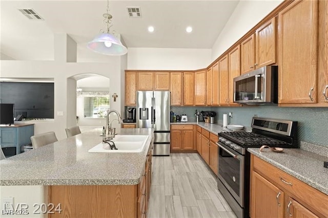 kitchen featuring sink, a kitchen breakfast bar, stainless steel appliances, and a kitchen island with sink