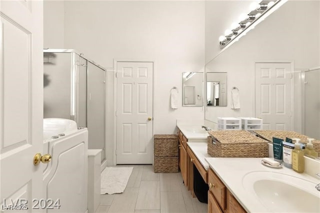 bathroom featuring a high ceiling, vanity, independent shower and bath, and washer / dryer