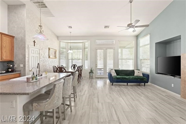 kitchen featuring ceiling fan, light wood-type flooring, a breakfast bar area, and pendant lighting