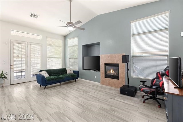 interior space featuring ceiling fan, a tiled fireplace, and lofted ceiling