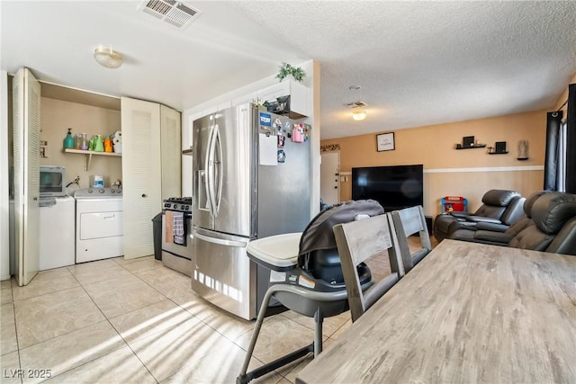 kitchen featuring washing machine and clothes dryer, light tile patterned floors, appliances with stainless steel finishes, and a textured ceiling