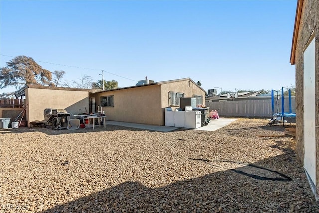 rear view of house with a trampoline and a patio area