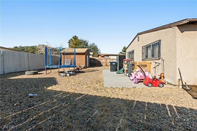 view of yard featuring a playground, a trampoline, and a storage unit