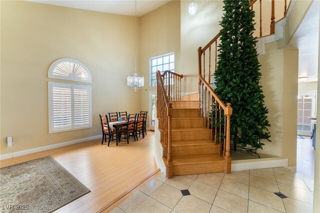 staircase with a high ceiling, hardwood / wood-style floors, and an inviting chandelier