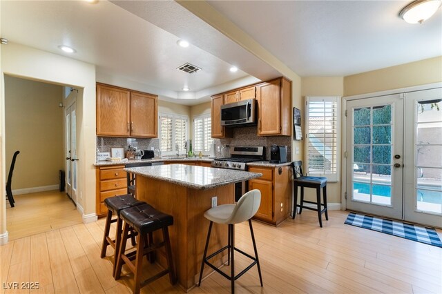 kitchen with french doors, a kitchen breakfast bar, stainless steel appliances, and a kitchen island