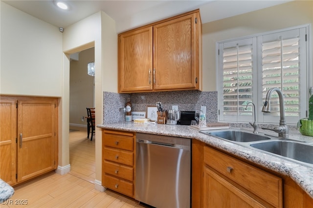 kitchen featuring dishwasher, decorative backsplash, sink, light wood-type flooring, and light stone counters