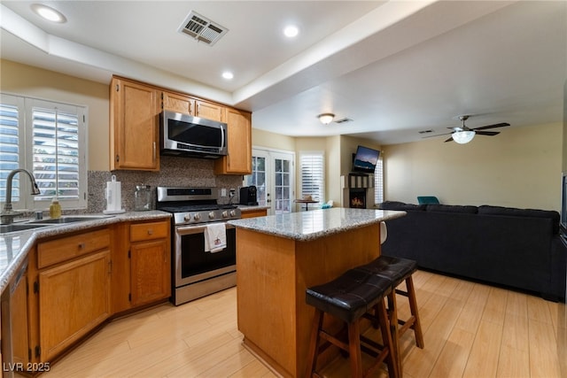 kitchen with backsplash, a center island, a kitchen bar, sink, and appliances with stainless steel finishes