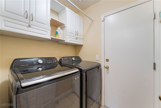 clothes washing area featuring washer and dryer and cabinets