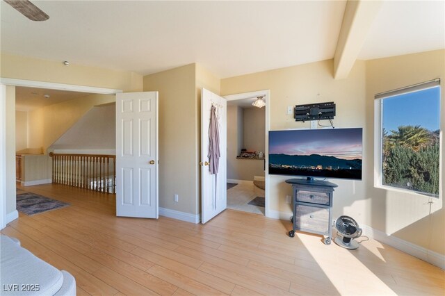 living room featuring lofted ceiling with beams and light hardwood / wood-style flooring