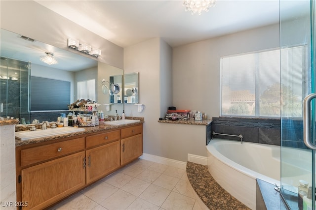 bathroom with a relaxing tiled tub, vanity, and tile patterned flooring