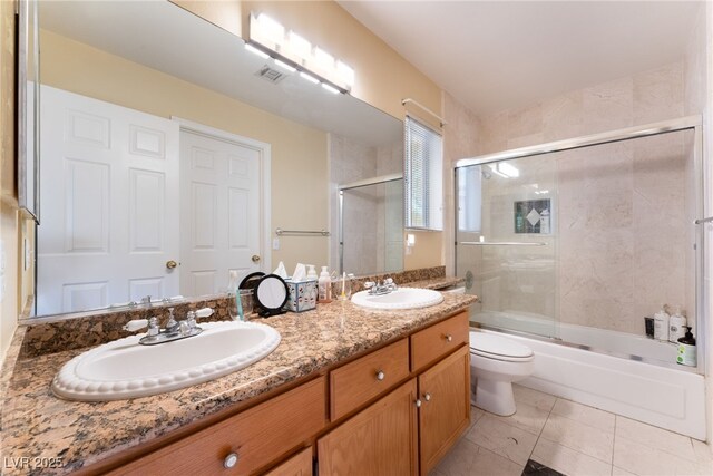 full bathroom with toilet, bath / shower combo with glass door, tile patterned flooring, and vanity