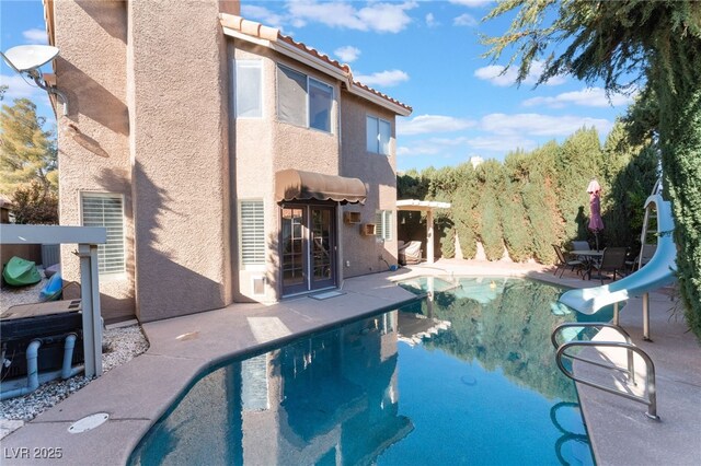 view of swimming pool with a water slide and a patio