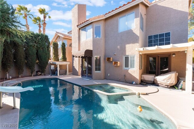 back of property featuring a swimming pool with hot tub and a patio area