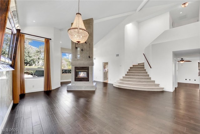 unfurnished living room with a fireplace, ceiling fan with notable chandelier, dark hardwood / wood-style floors, and high vaulted ceiling