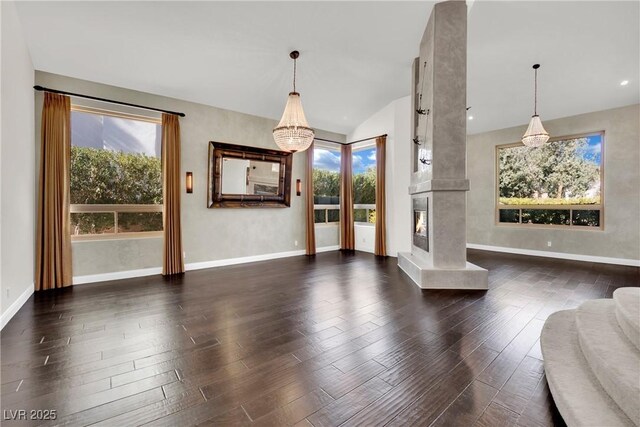 unfurnished living room with dark wood-type flooring, a high end fireplace, and a notable chandelier