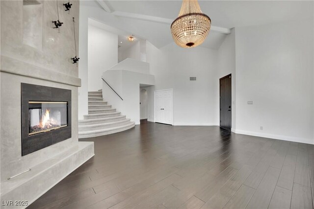 unfurnished living room featuring vaulted ceiling with beams, dark hardwood / wood-style flooring, and an inviting chandelier