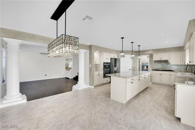 kitchen with white cabinetry, a kitchen island, stainless steel fridge, and sink