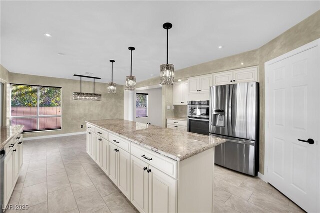 kitchen with white cabinets, a kitchen island, decorative light fixtures, stainless steel appliances, and light stone counters