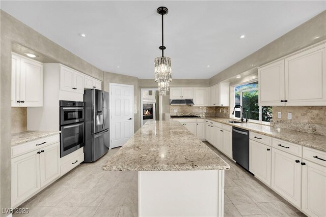 kitchen with hanging light fixtures, white cabinets, a center island, and black appliances