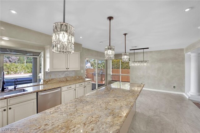 kitchen featuring light stone counters, sink, hanging light fixtures, and dishwasher