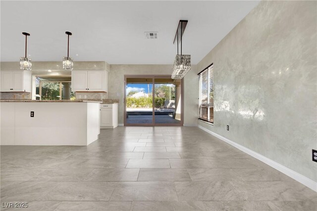 kitchen with hanging light fixtures, white cabinets, decorative backsplash, and light stone countertops