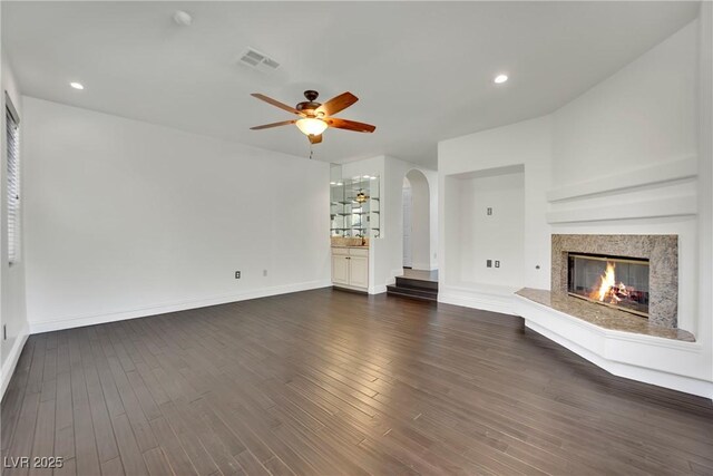 unfurnished living room with ceiling fan, a fireplace, and dark hardwood / wood-style flooring