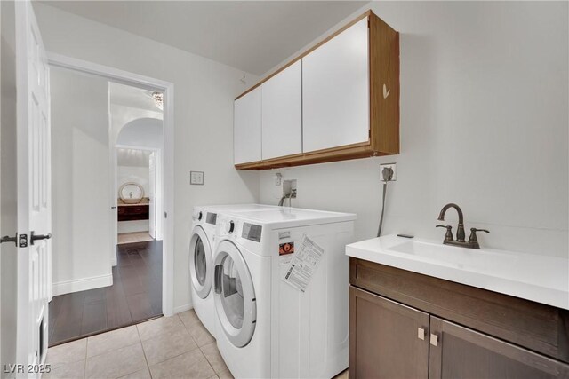 laundry room with cabinets, light tile patterned floors, and washer and dryer