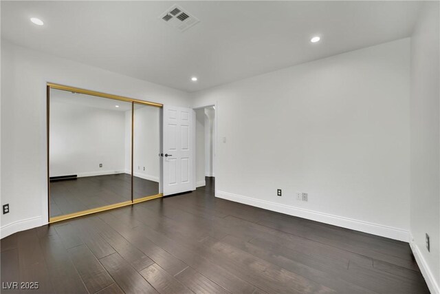 unfurnished bedroom featuring a closet and dark hardwood / wood-style flooring