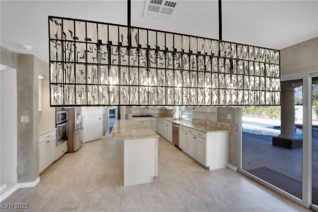 kitchen featuring light stone countertops, white cabinetry, and a kitchen island