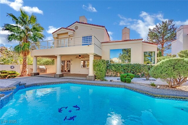 back of house featuring a balcony, a fenced in pool, a patio, ceiling fan, and area for grilling