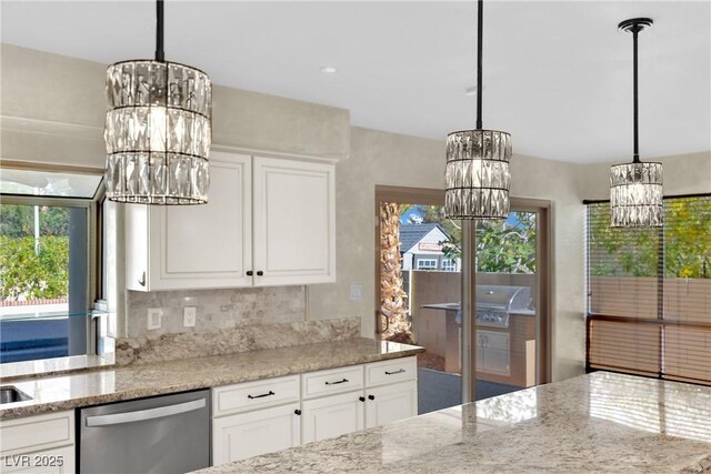 kitchen with stainless steel dishwasher, white cabinets, hanging light fixtures, and light stone counters