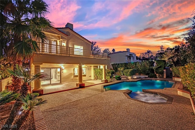 pool at dusk with a patio area