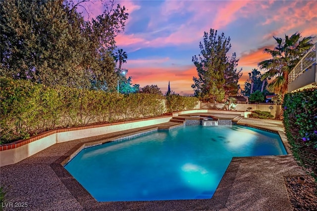 pool at dusk with an in ground hot tub