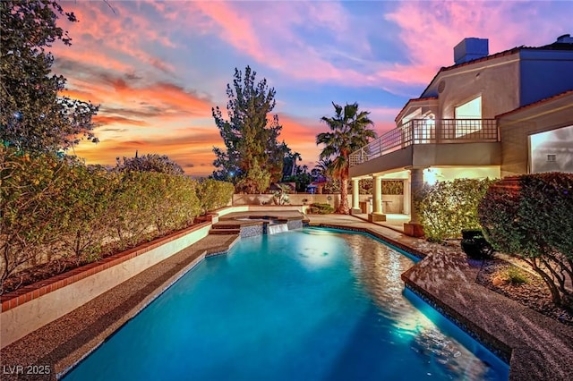 pool at dusk with an in ground hot tub and a patio area