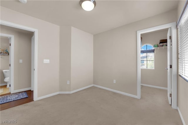 unfurnished bedroom with ensuite bathroom and light colored carpet