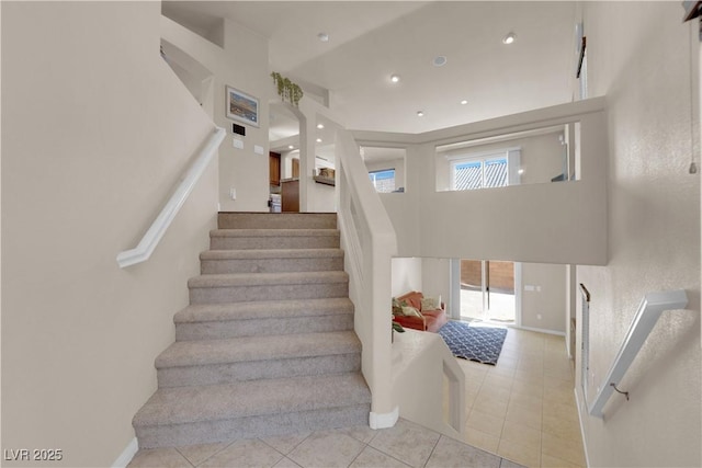 staircase featuring a towering ceiling and tile patterned flooring