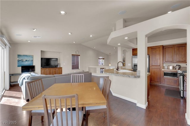 dining room with vaulted ceiling, dark hardwood / wood-style flooring, and sink