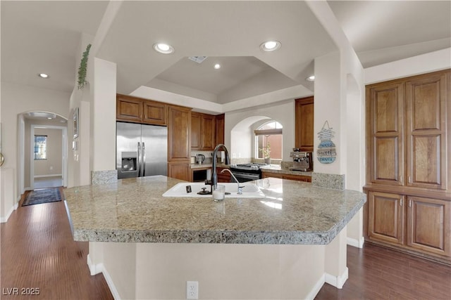 kitchen featuring a kitchen bar, kitchen peninsula, dark hardwood / wood-style floors, lofted ceiling, and stainless steel built in refrigerator